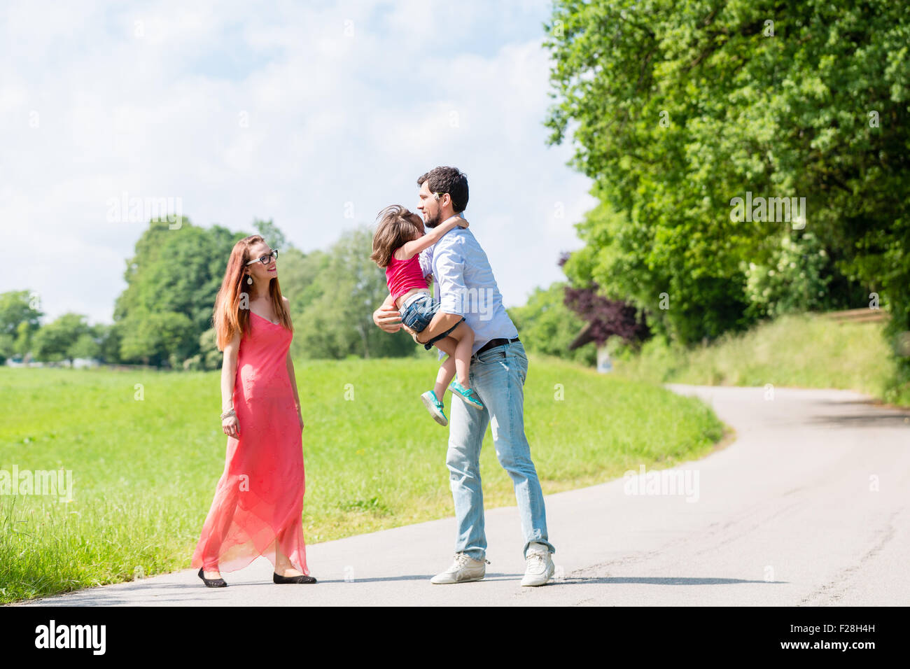 Mamma, papà e figlia avente a piedi sul percorso in estate Foto Stock