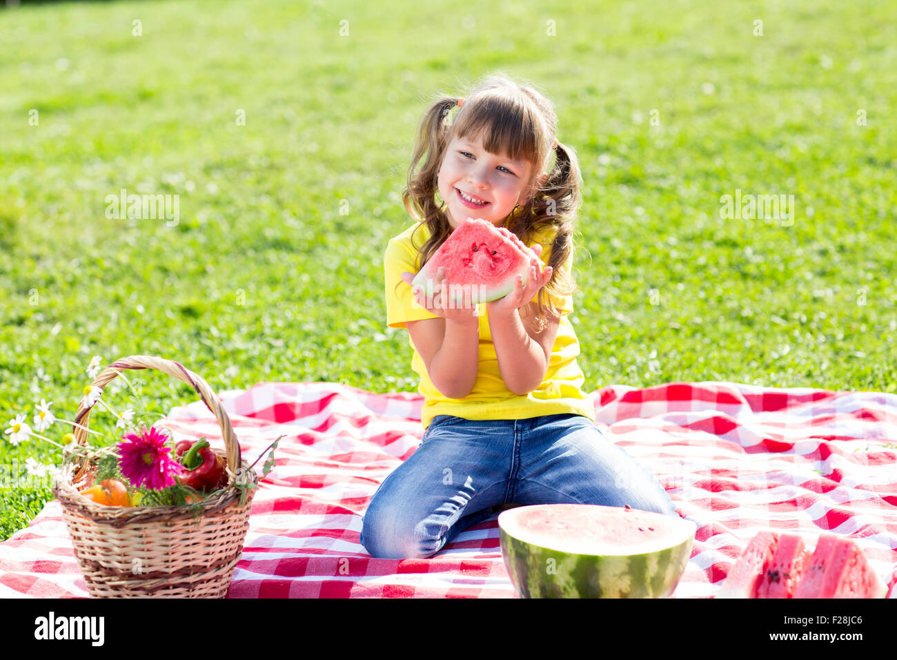 Ragazza carina mangiando anguria sull'erba in estate Foto Stock