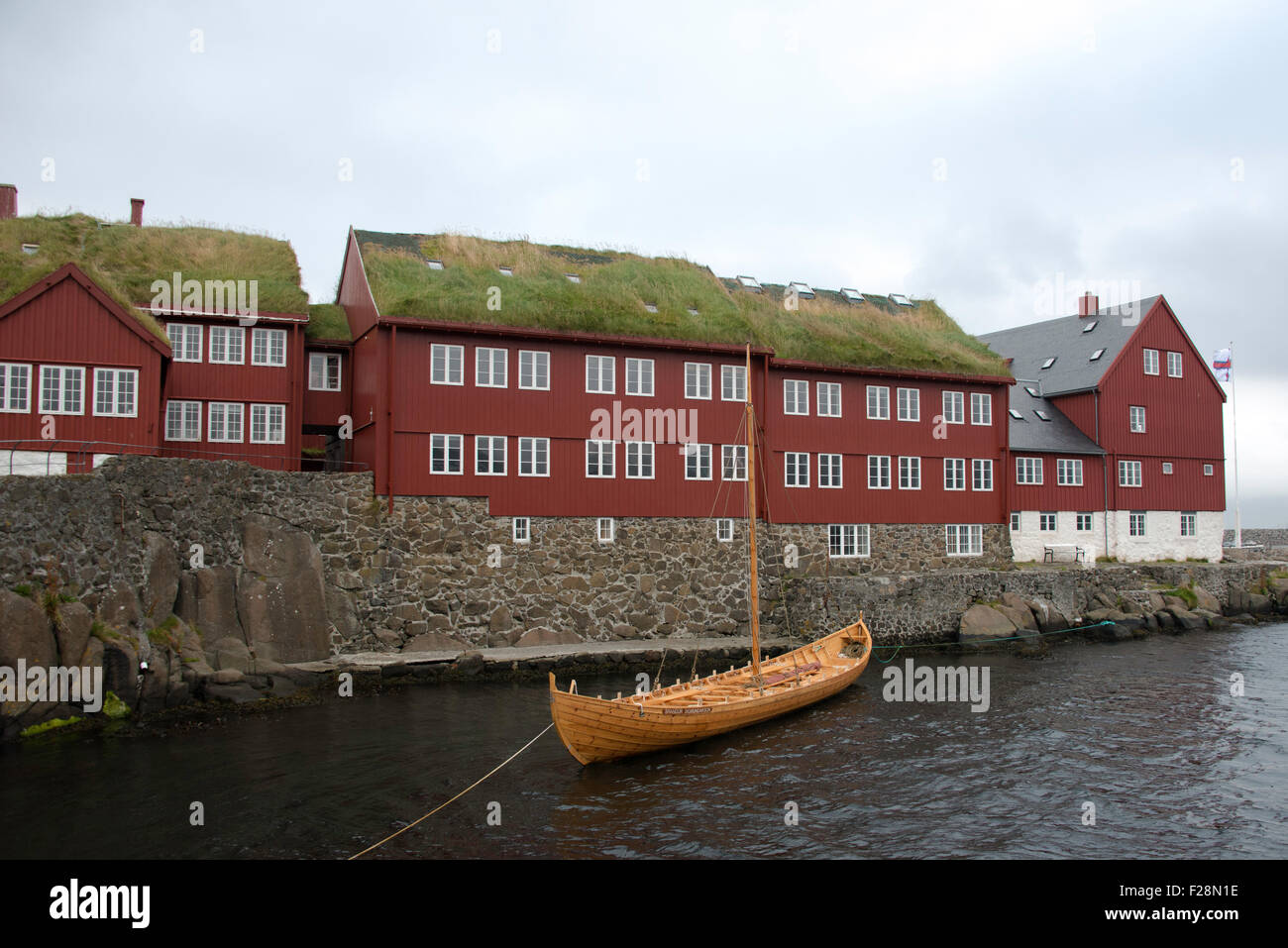Barca tradizionale fuori Tinganes edifici governativi a capitale Torshavn, Isole Faerøer Foto Stock