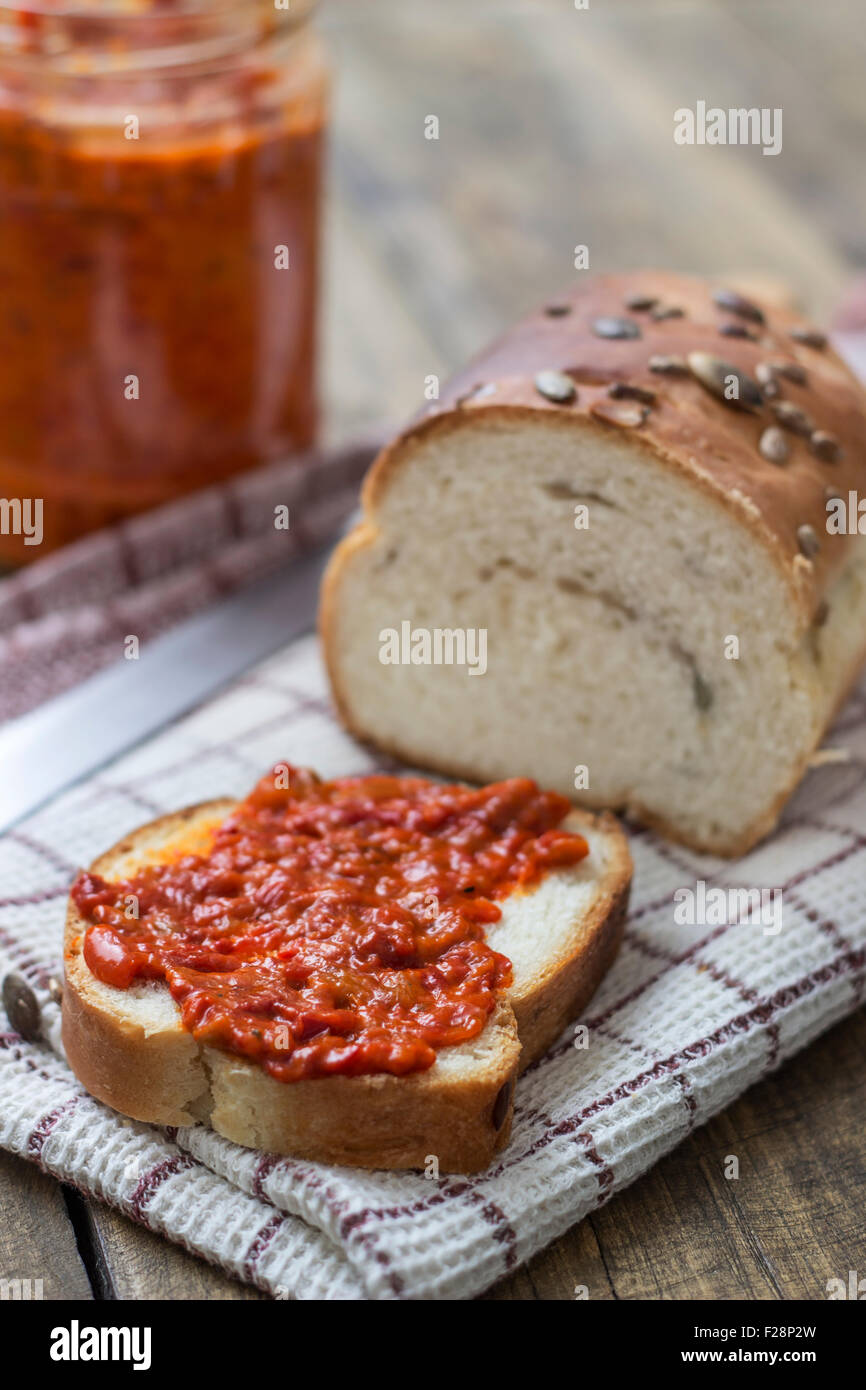Fetta di pane cosparsa con chutney sul tavolo di legno Foto Stock