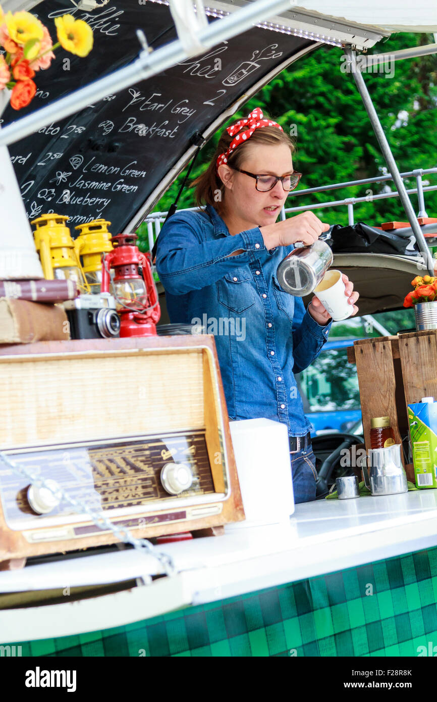 Versare il caffè che servono bevande al di fuori di un vecchio bus timer decorate con artefatti retrò al summer Swan nel mercato Dordrecht Foto Stock