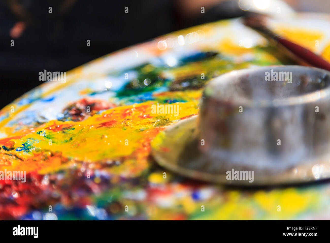 Olio artisti tavolozza di colori con vari colori e tocchi di vernice wit un effetto bokeh di fondo Foto Stock