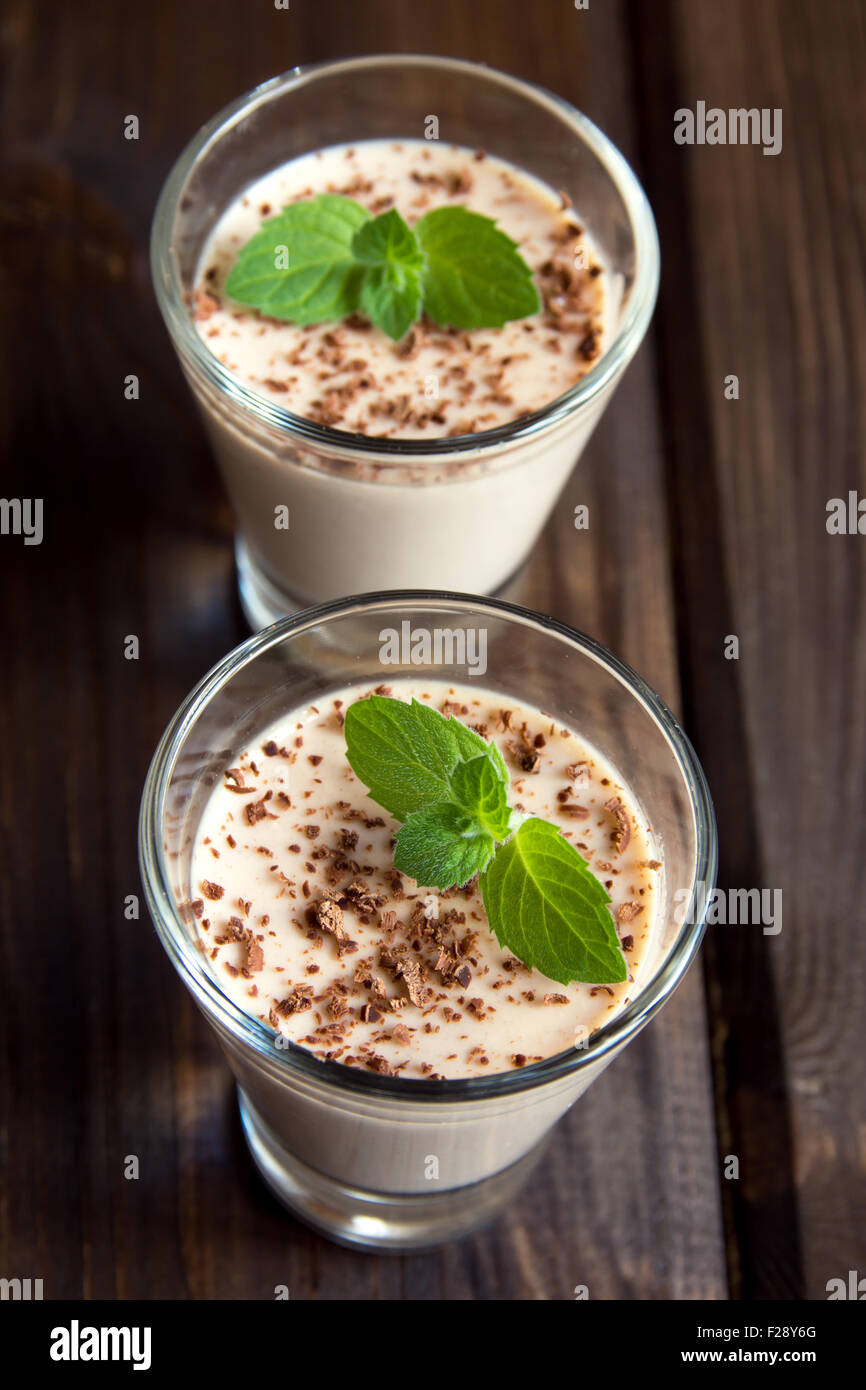 Il cioccolato Panna cotta dessert con la menta nella porzione occhiali scuri su sfondo di legno Foto Stock
