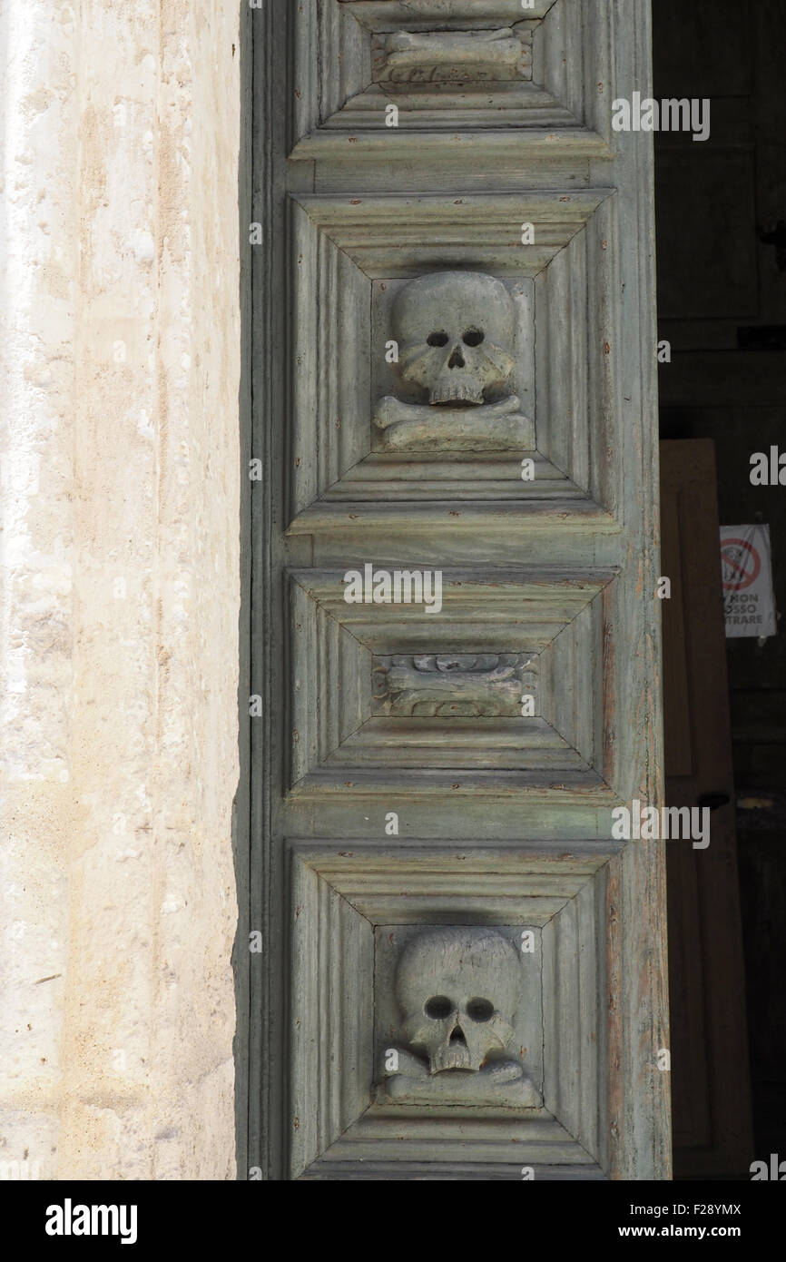 Porta in legno sculture del cuscinetto di teschi e le ossa in ingresso alla Chiesa del Purgatorio, Matera, Basilicata, Italia. Foto Stock