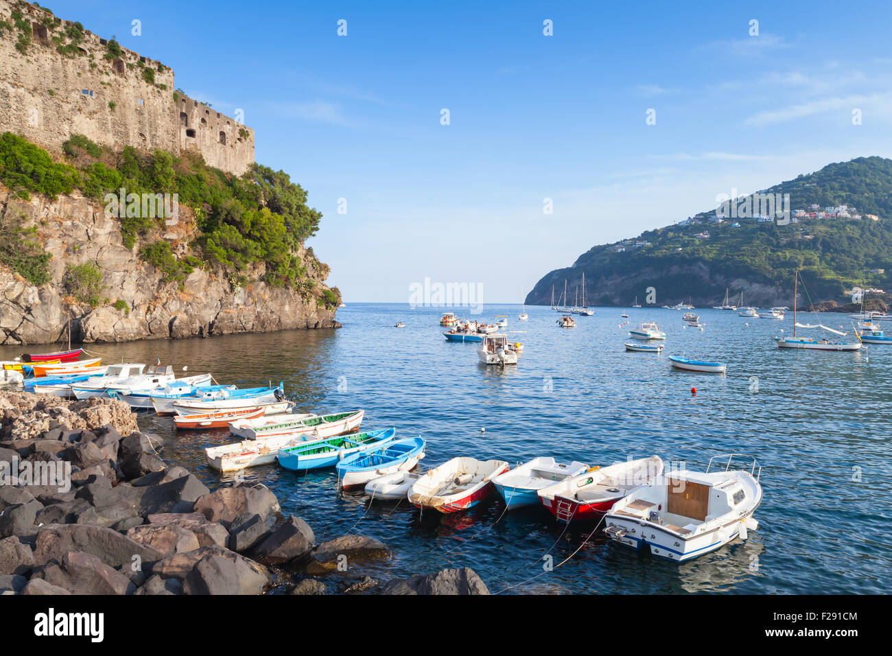 Il paesaggio costiero di Ischia Porto con Castello Aragonese e barche colorate Foto Stock