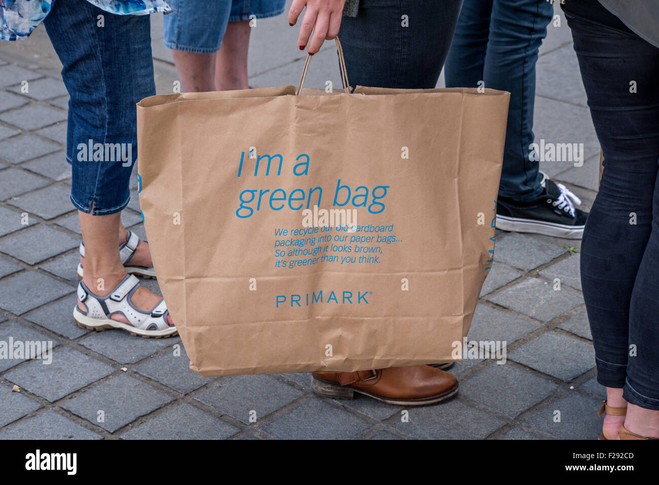 Un cliente che detiene un Primark " verde " carta marrone sacchetto realizzato da cartone riciclato e sacchi di carta. Foto Stock