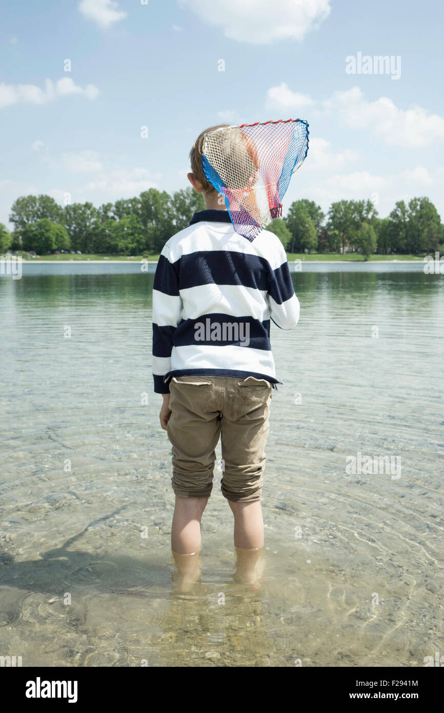 Vista posteriore di un ragazzo azienda rete da pesca nel lago, Baviera, Germania Foto Stock