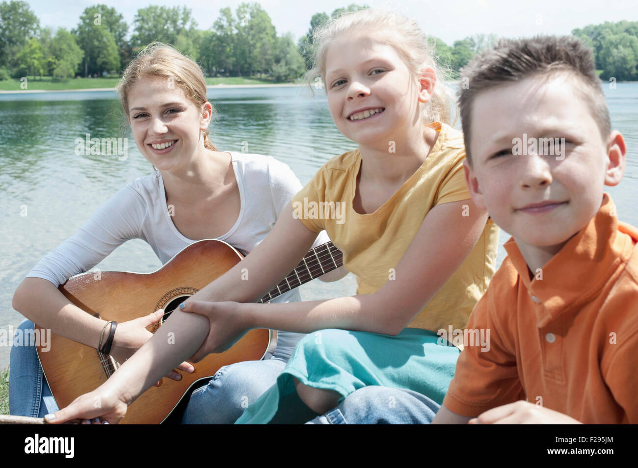 Giovane leader a suonare la chitarra con i suoi amici a Lakeside, Baviera, Germania Foto Stock