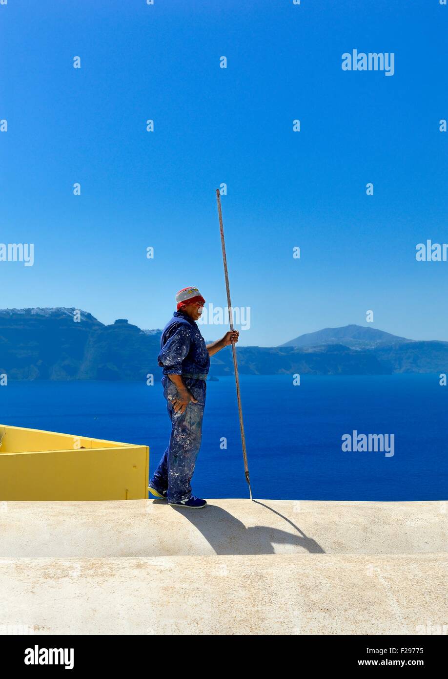 Uomo al lavoro su un tetto hotel sulla caldera,Santorini, Grecia Foto Stock