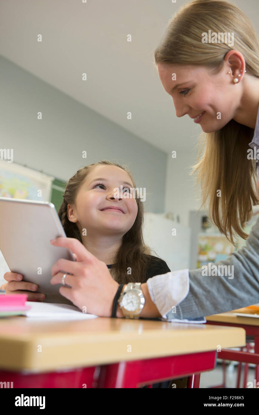 Insegnante di sesso femminile che mostra una ragazza qualcosa su digital tablet pc in aula, Monaco di Baviera, Germania Foto Stock