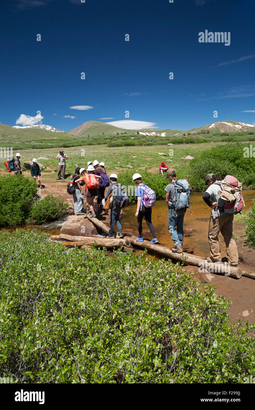 Georgetown, Colorado - Teenage membri di un sentiero equipaggio di manutenzione attraversare un flusso su un sentiero di montagna. Foto Stock