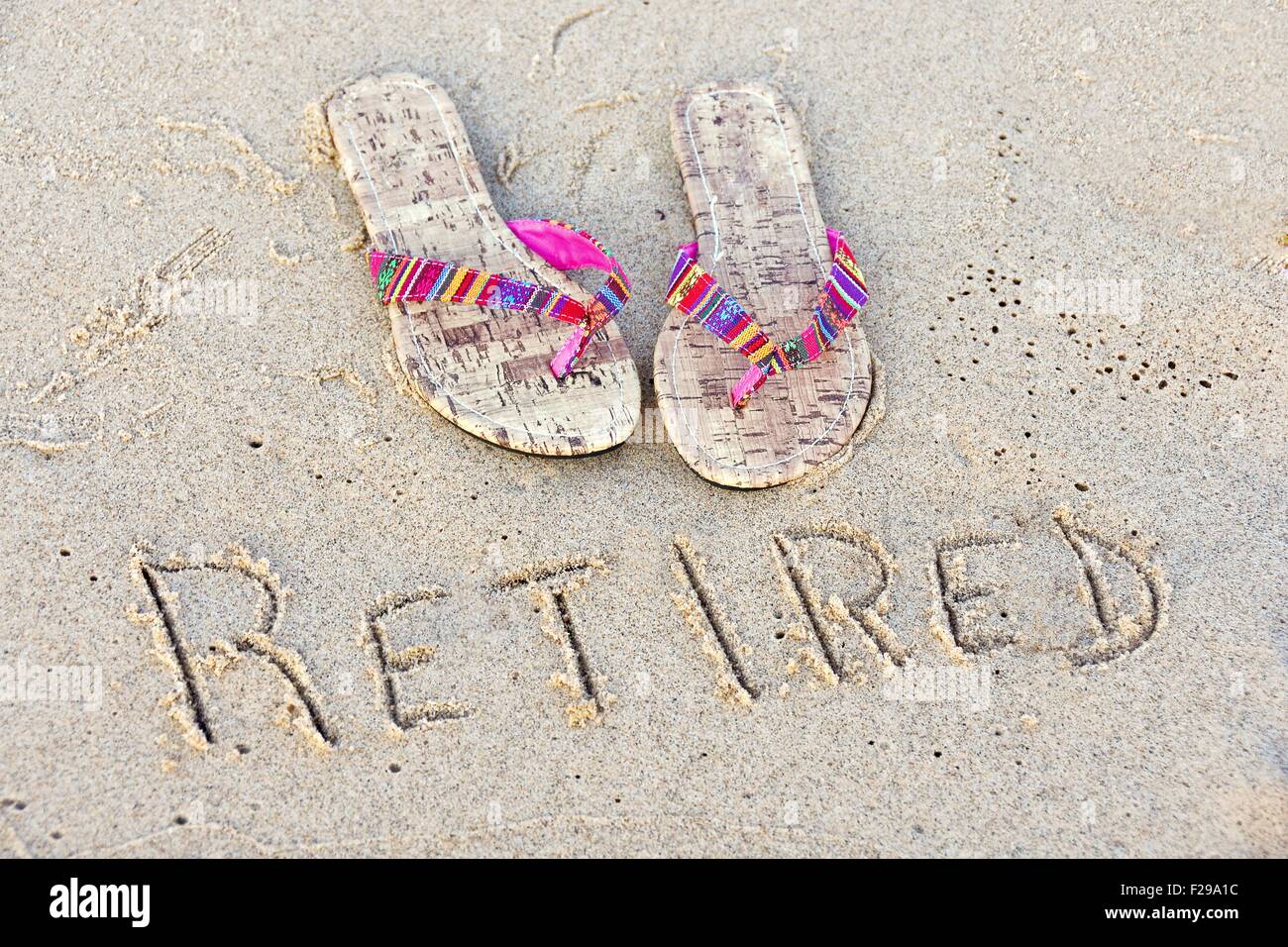 Coppia di flip-flop in spiaggia di sabbia con il pensionamento di segno. Foto Stock