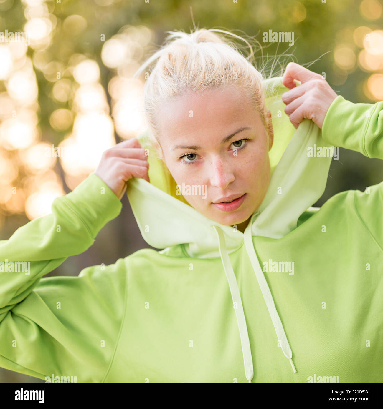 Fiducioso sportivo da donna che indossa alla moda felpa con cappuccio verde. Foto Stock
