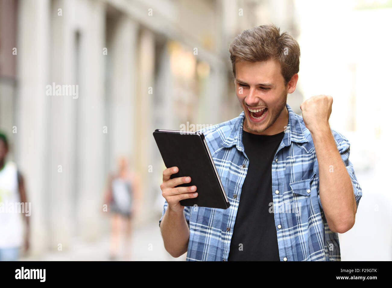 Euforico vincitore uomo urlando con una pastiglia in strada Foto Stock