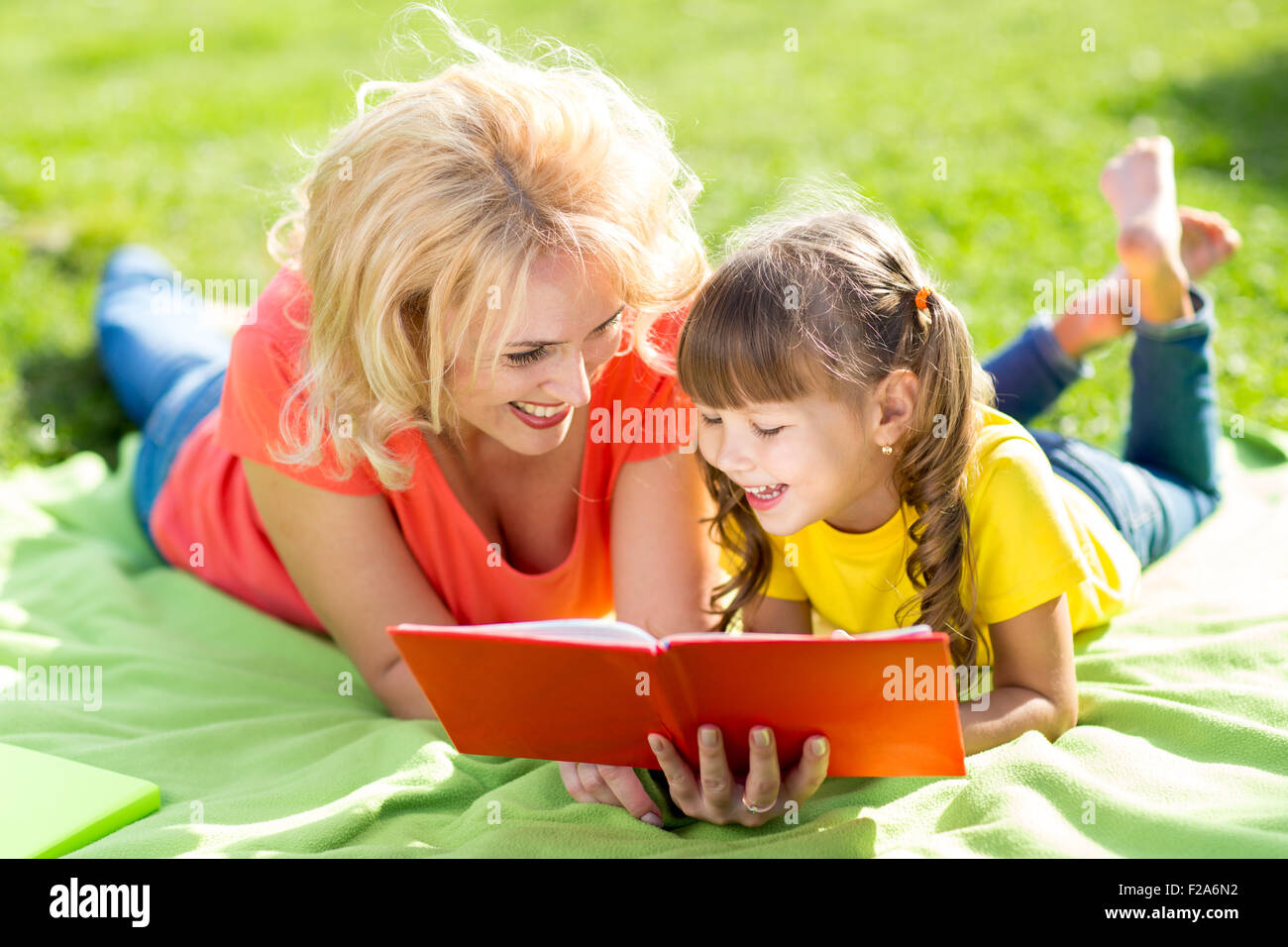Felice madre con la figlia nel parco libro di lettura Foto Stock
