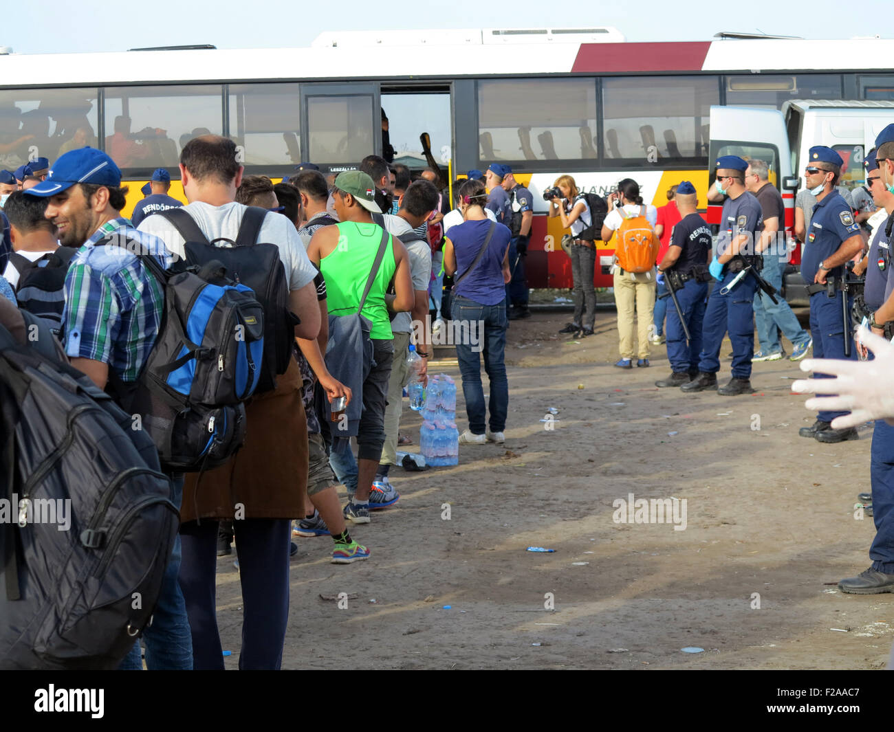 Oeszke, Ungheria. Xiv Sep, 2015. Ungherese di scorta di polizia per i rifugiati in attesa autobus poco prima della chiusura della sezione finale del la recinzione di confine tra Ungheria e Serbia vicino Oeszke, Ungheria, 14 settembre 2015. I bus sono tenuto ai rifugiati di preparati centri di accoglienza. Foto: Thomas Brey/dpa/Alamy Live News Foto Stock