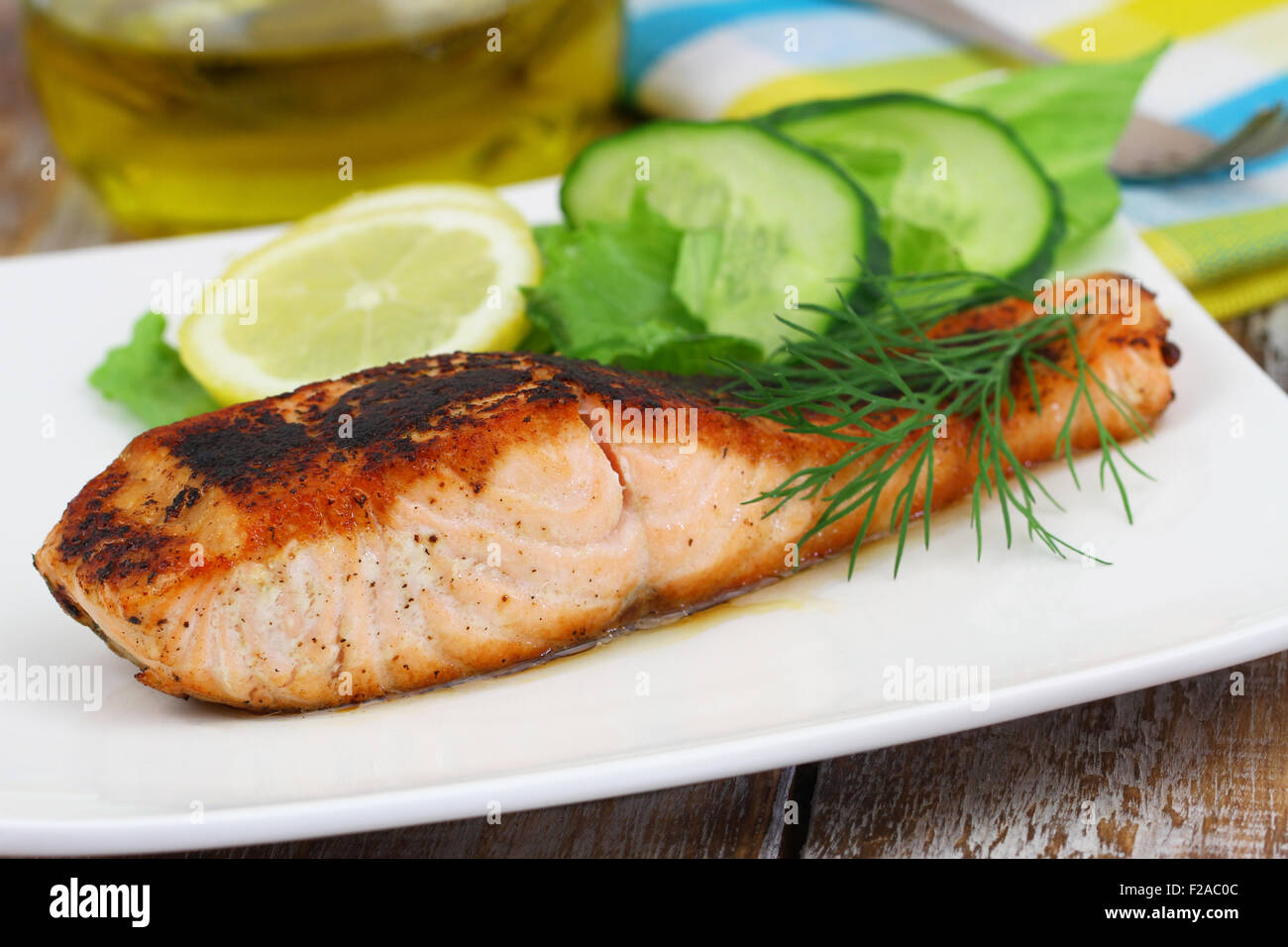 Salmone alla griglia con limone e insalata di contorno sulla piastra bianca Foto Stock