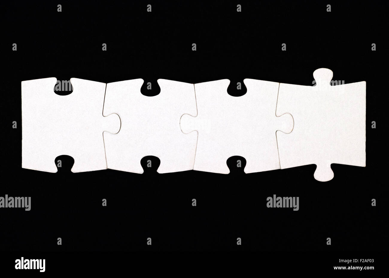Quattro pezzi di un puzzle sono collegati insieme su sfondo nero Foto Stock