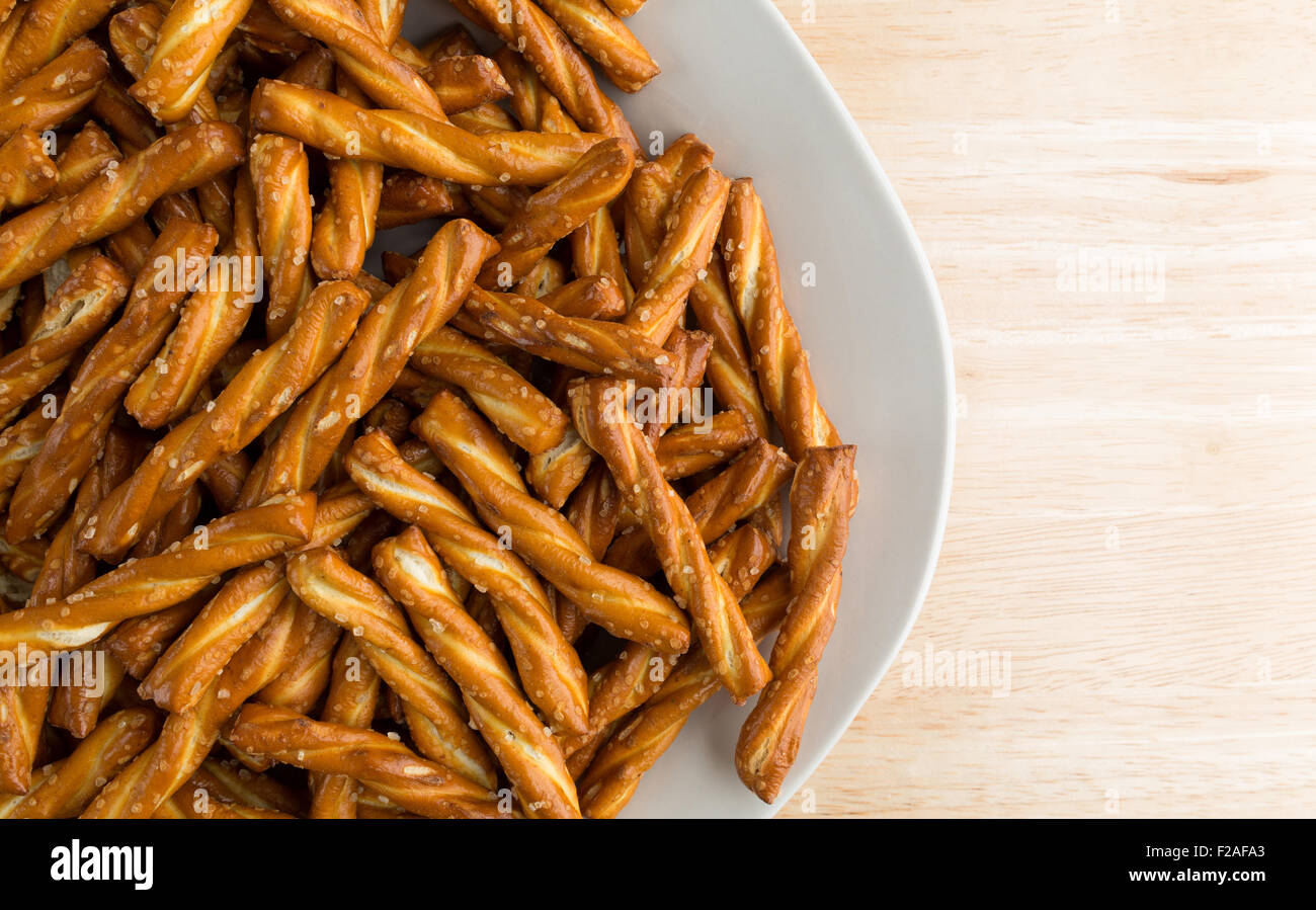 Top vista ravvicinata di una piastra riempita con pretzel intrecciato sulla cima di un legno tavolo illuminato con luce naturale. Foto Stock