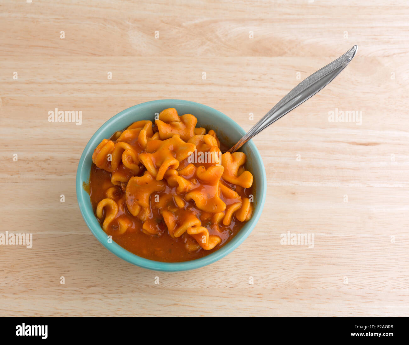 A che serve di conserve di pasta lasagne in una ciotola verde con una forcella inserita nel cibo su una tavola di legno top Foto Stock