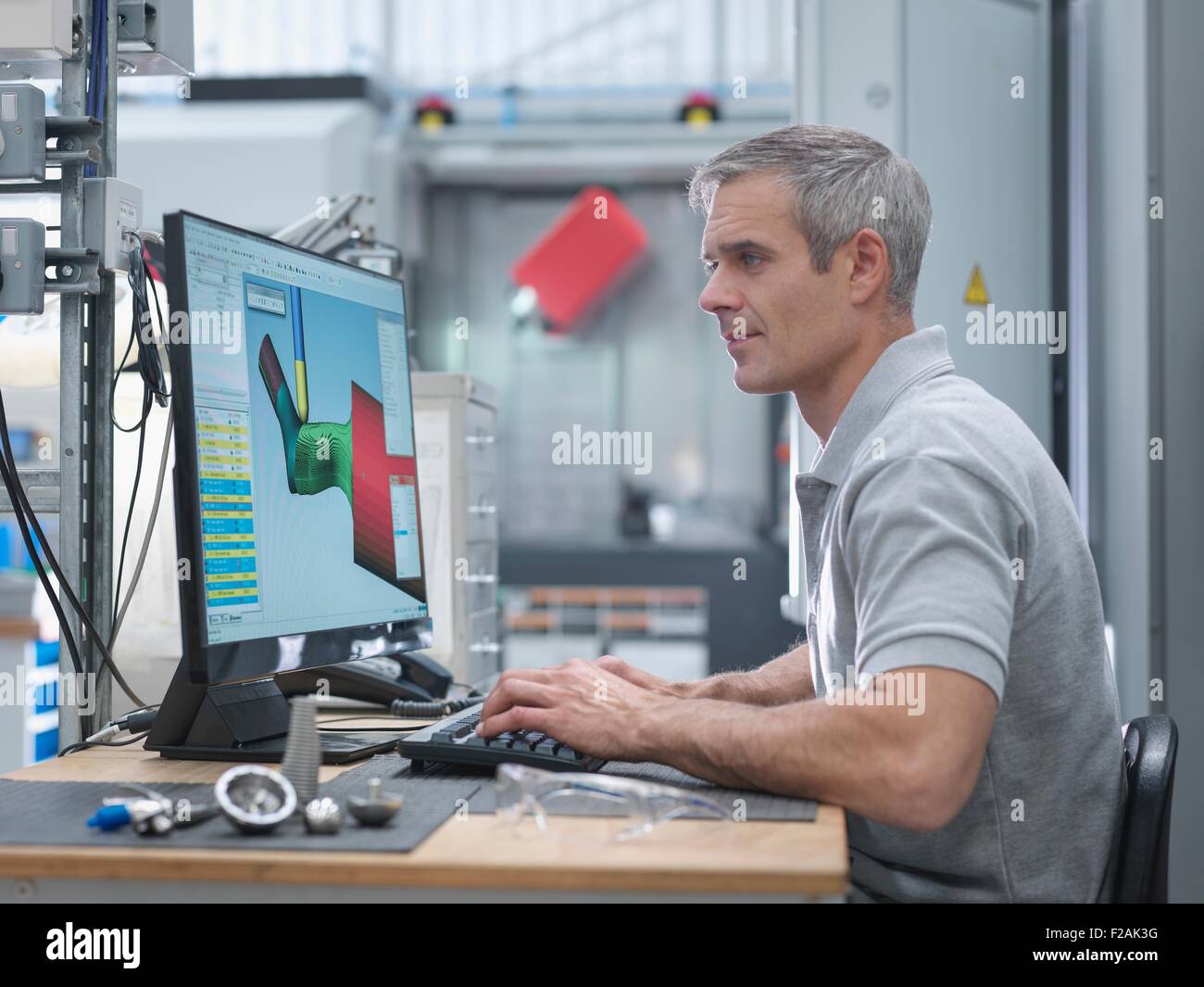 Ingegnere guardando tornio CNC progressi sullo schermo in fabbrica ortopedico Foto Stock