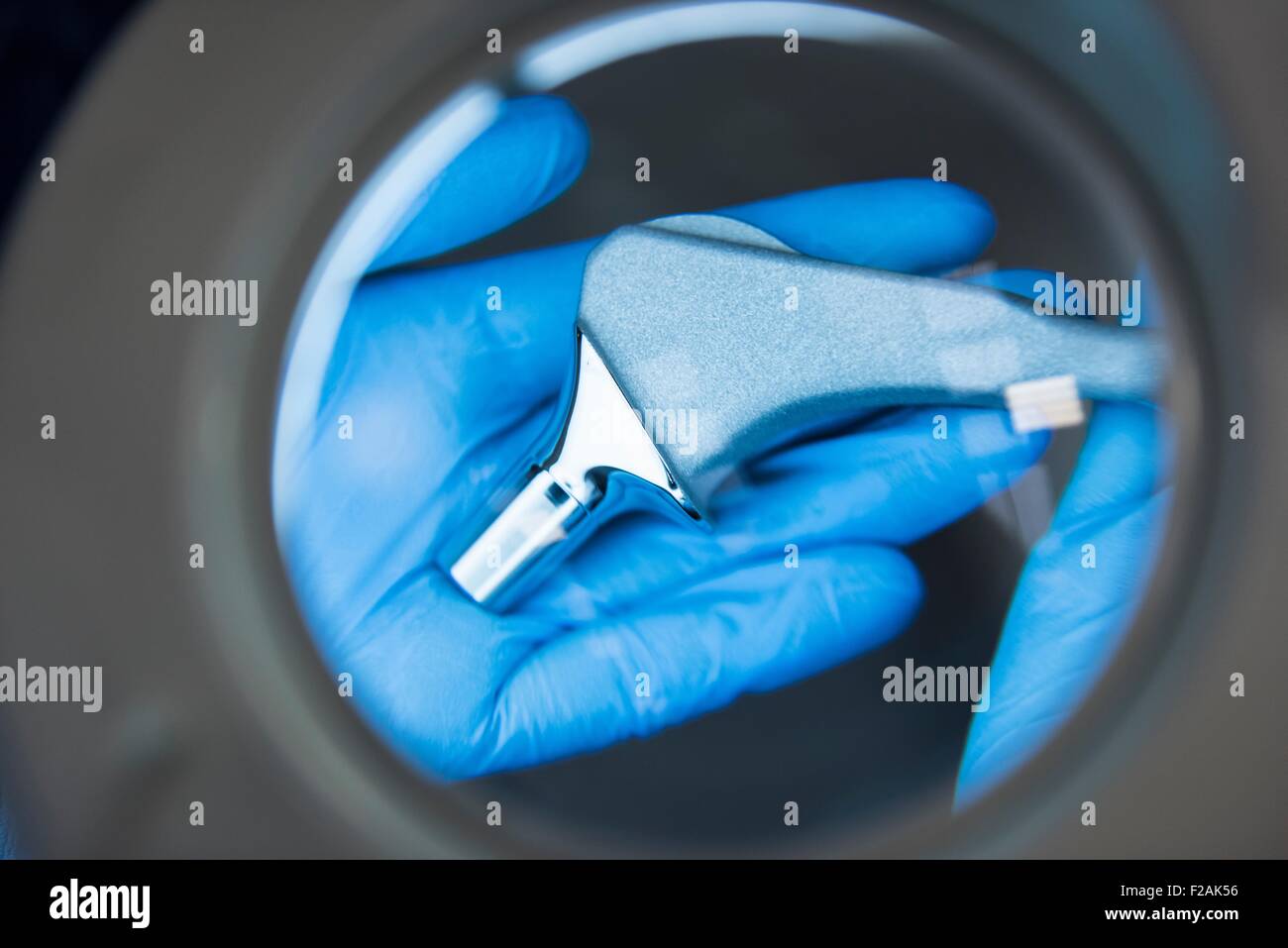 Ingegnere ispezione articolazione artificiale dell'anca attraverso la lente di ingrandimento ortopedico in fabbrica, close up Foto Stock