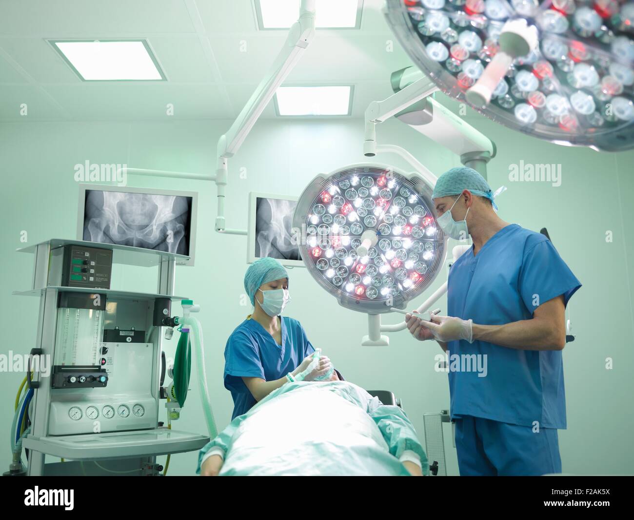 Chirurgo ortopedico infermiere e preparare il paziente per la chirurgia dell'anca in sala operatoria Foto Stock