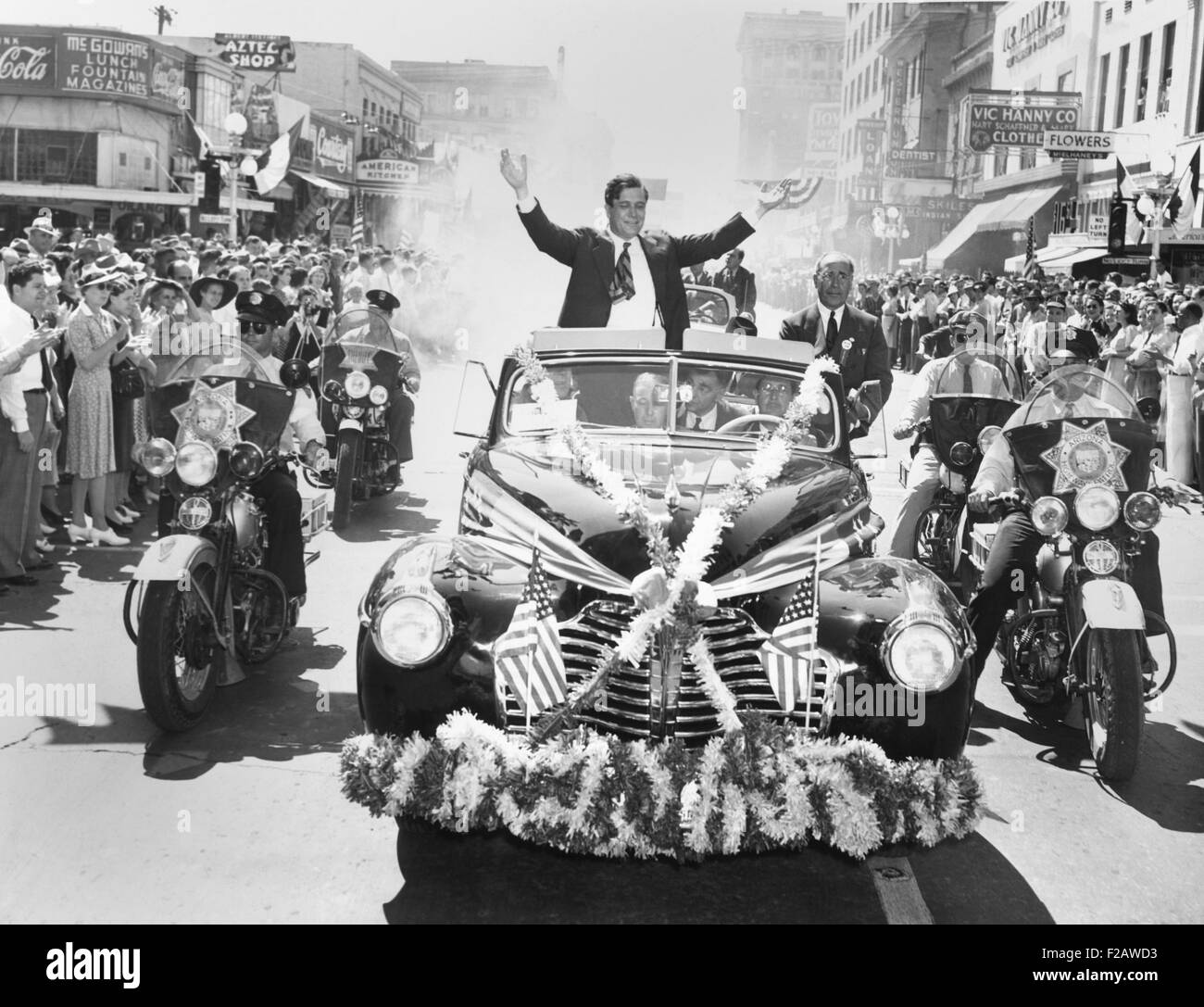 Wendell Willkie accetta gli applausi della folla a Phoenix, Arizona, sul Sett. 19, 1940. La sua bandiera e adornato di fiori convertibile è fiancheggiata da motocicletta di polizia. (CSU 2015 11 1396) Foto Stock