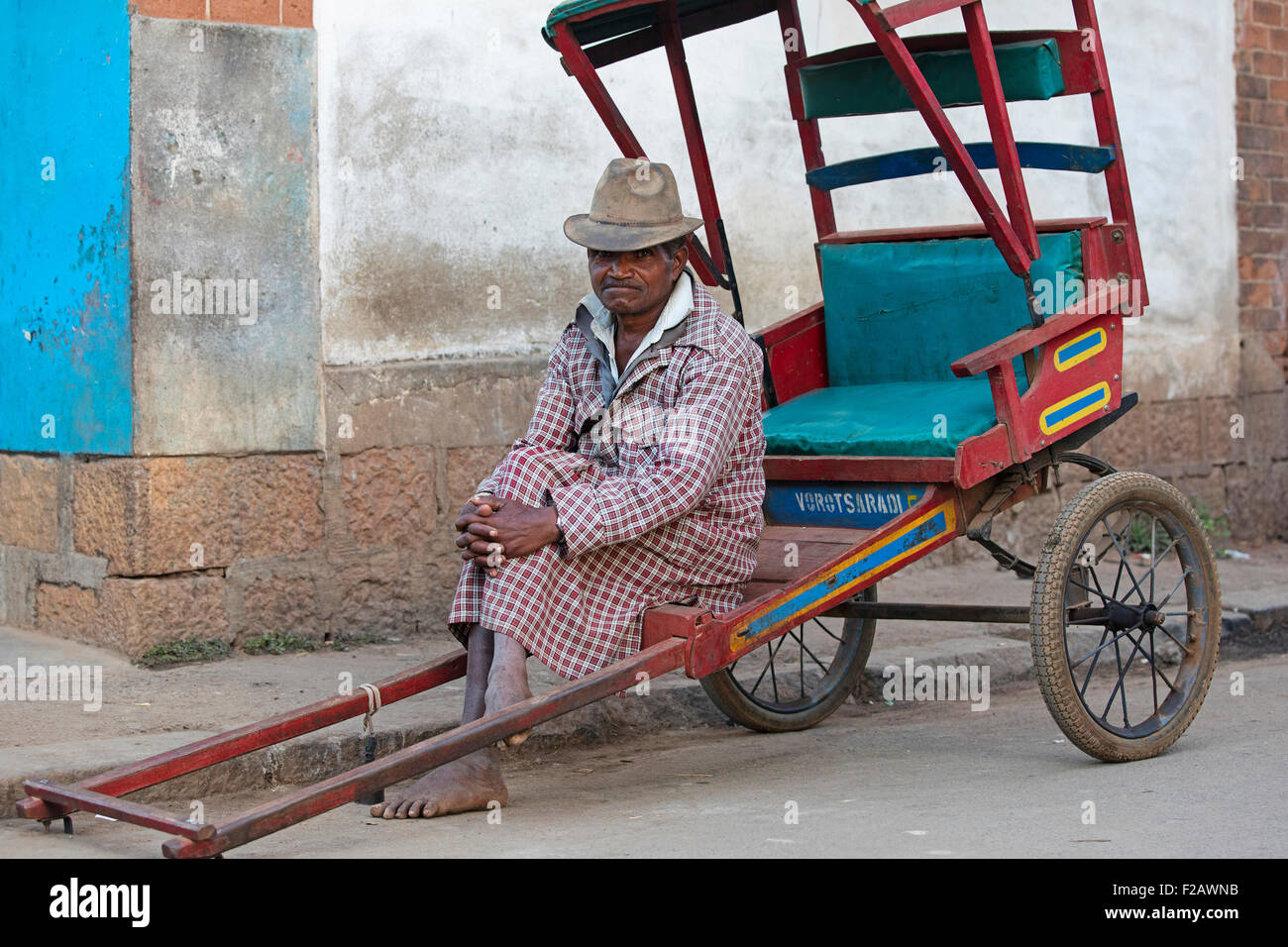 Vecchio pousse malgascio-pousse driver, in attesa per i clienti nelle vie della città Antsirabe, Vakinankaratra, Madagascar, Africa Foto Stock