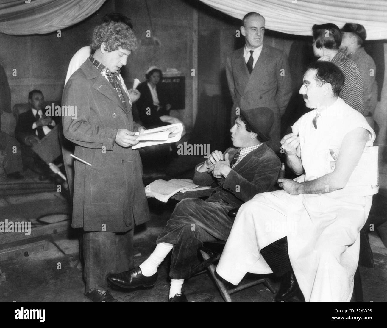 Gli Harpo, Chico e Groucho Marx sul set di MGM's movie, una giornata di gare. Ottobre 8, 1937. Il regista Sam permanente del legno in sfondo a destra. Gli Harpo Marx sta leggendo le sue azioni da uno script. (CSU 2015 11 1251) Foto Stock