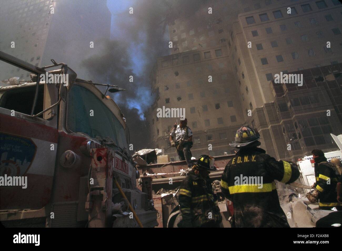 I vigili del fuoco in mezzo a detriti seguenti settembre undicesimo attacco terroristico contro il World Trade Center. Sullo sfondo sono danneggiati edifici del World Financial Center di New York City, Sett. 11, 2001. (BSLOC 2015 2 44) Foto Stock
