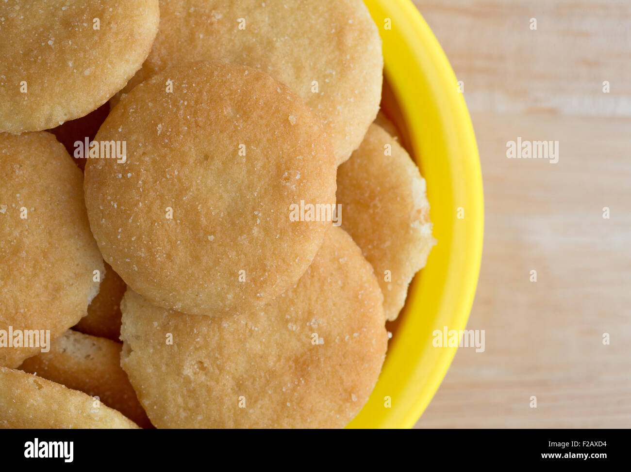 Top chiudere la vista di un piccolo giallo ciotola riempita con vaniglia aromatizzato cookie di wafer su una tavola di legno top Foto Stock