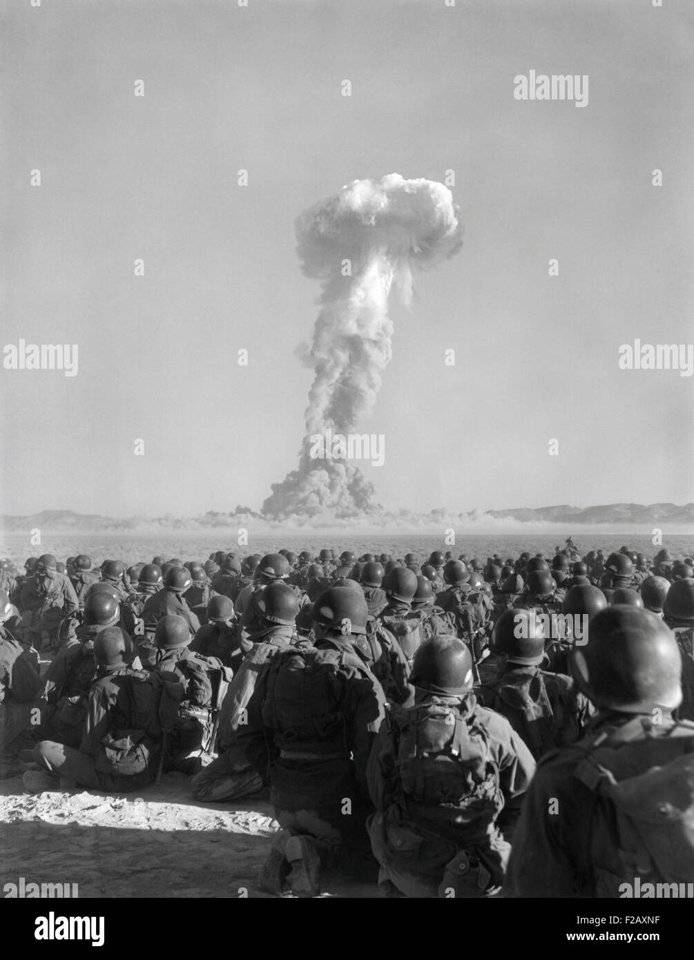 Esercizio Desert Rock, nov. 1, 1951. Gli uomini di U.S. Esercito xi Airborne Division, guardare un pennacchio di radio-attivi Aumento di fumo a Yucca Flats. Soldati manovre condotte la limitazione della dose di esposizione alle radiazioni limite era stato fissato in 3,0 rem. Tuttavia, 68 soldati hanno ricevuto le esposizioni in eccesso da oltre 3 a 10 rem (Roentgen equivalent man). Un rem porta con sé un 0,055% di possibilità di eventualmente lo sviluppo del cancro. (BSLOC 2015 2 14) Foto Stock
