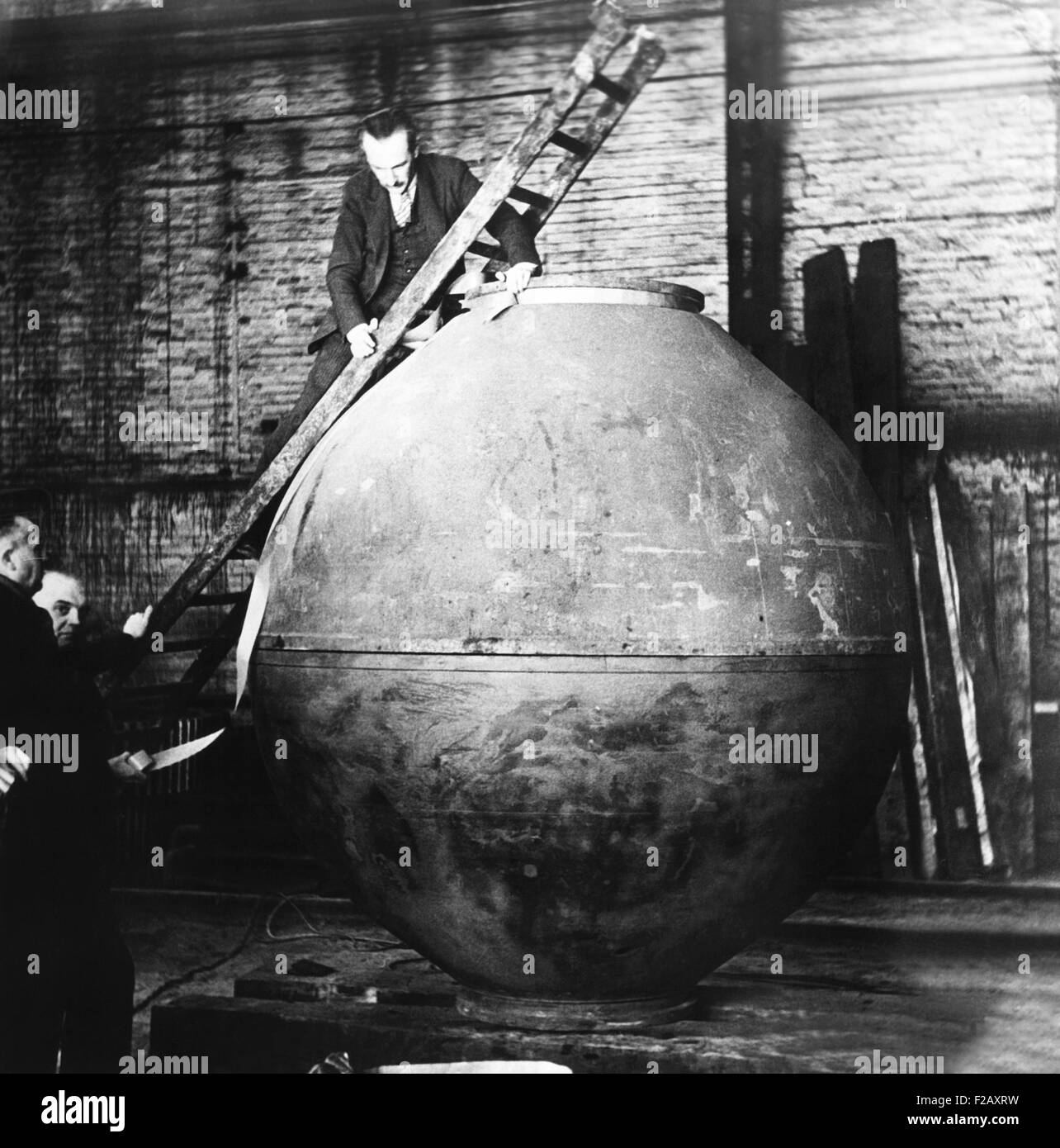 Auguste Piccard su una scala esaminando la "gondola" la costruzione nella sua bottega. La forma sferica della capsula di alluminio è stata pressurizzata per consentire la salita ad alta altitudine un senza pressione adatta. Ca. 1930-1932. Il 27 maggio 1931, la capsula dovrebbe portare a buon fine la salita che porta Piccard e Charles Kipfer. (CSU 2015 9 985) Foto Stock