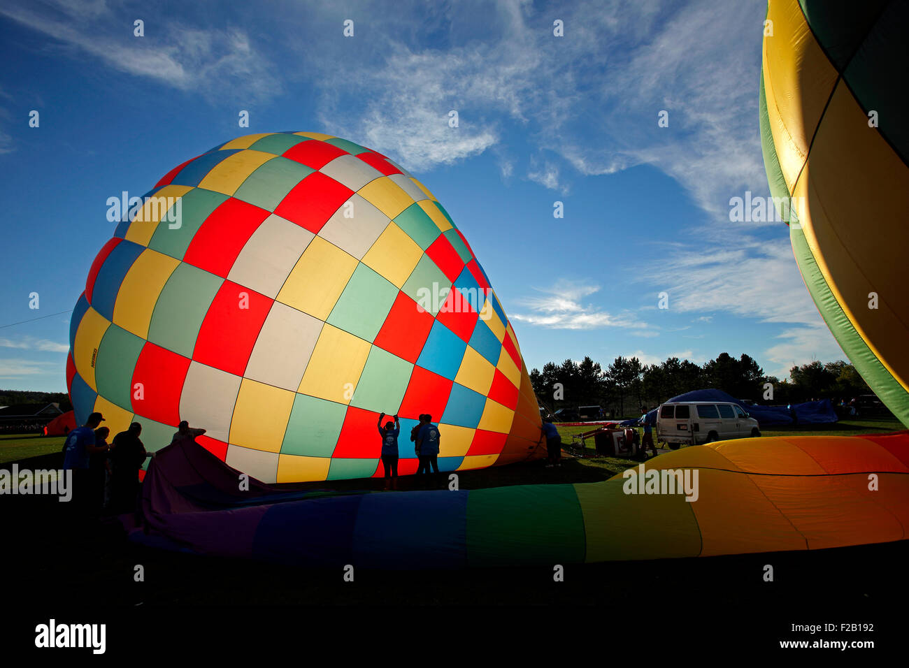 Sagome contro un gonfiaggio di una mongolfiera al trentesimo atlantico annuale International Balloon Fiesta, Sussex, NB, Canada. Foto Stock