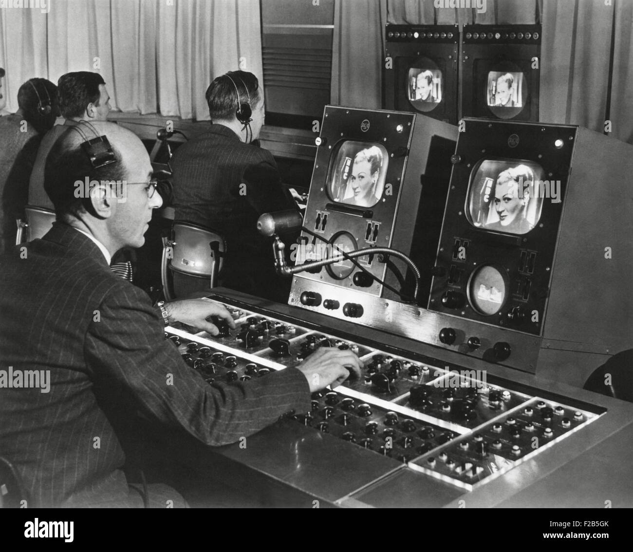 Studio televisivo engineer riceve diverse viste dell'immagine e utilizzare la complessa serie di quadranti per controllare il tono e la qualità Foto Stock