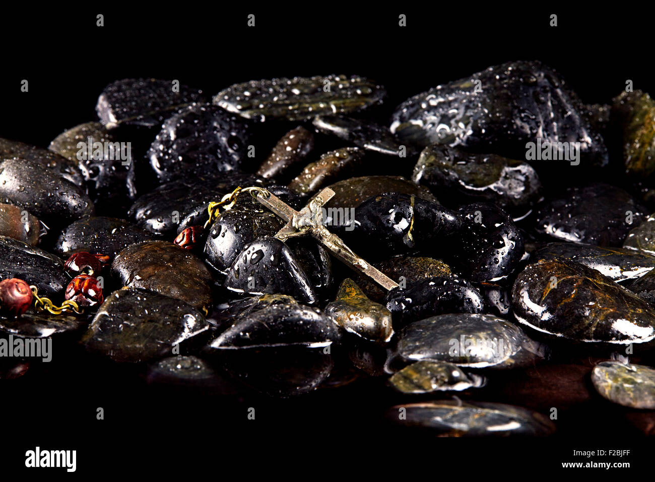 Vintage Rosario con argento crocifisso sul bagnato pietre nere Foto Stock