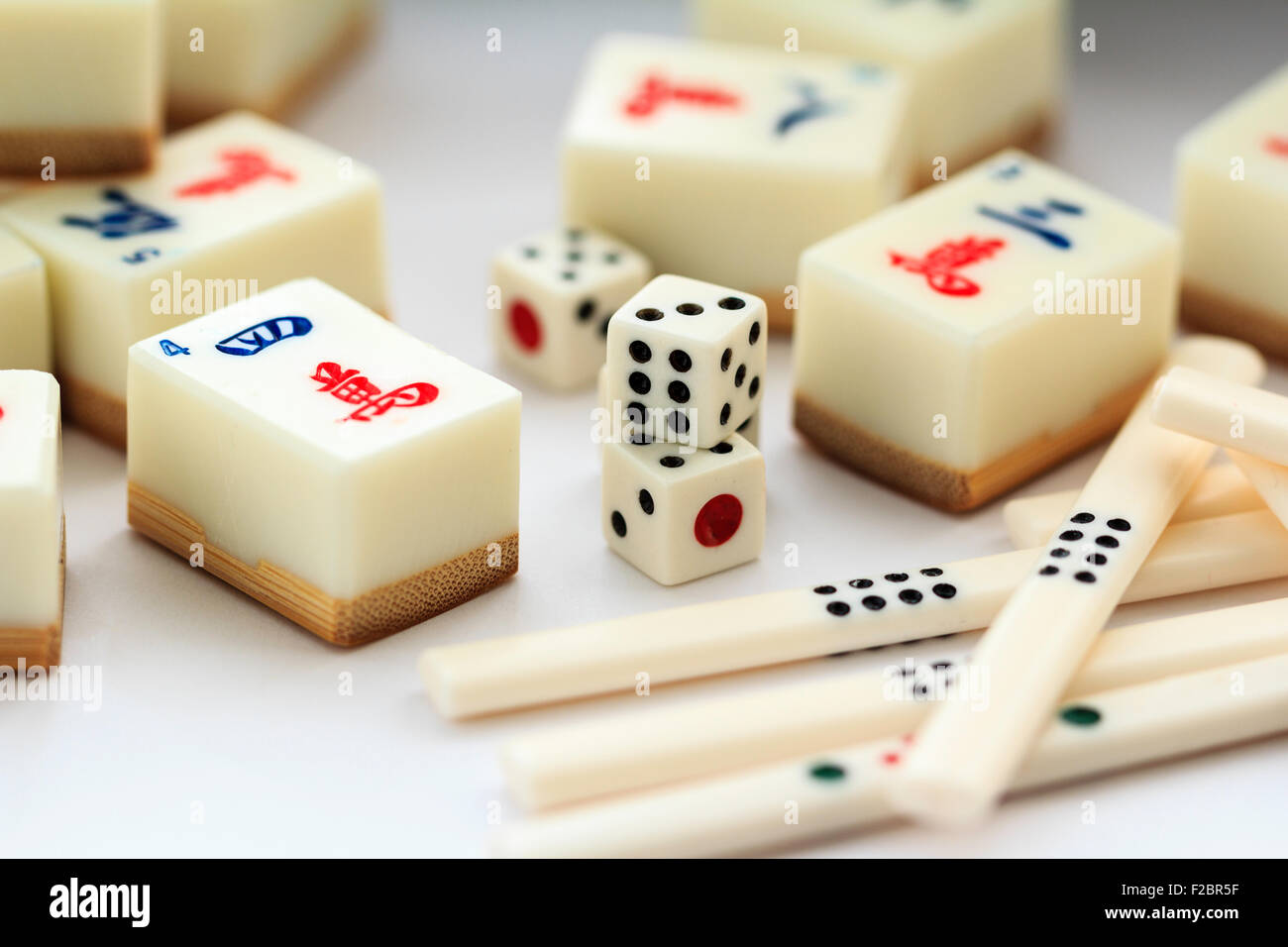 Mahjong Mah Jong il gioco d'azzardo set. Varie carte o piastrelle, dadi e alcuni contatori posa su sfondo bianco. Foto Stock