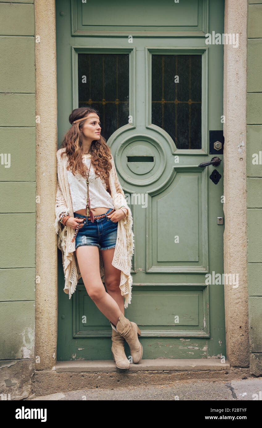 Malinconici longhaired hippy-cerca giovane donna in jeans corti,  coprispalle in maglia e camicia bianca in piedi al di fuori degli edifici  in stree Foto stock - Alamy