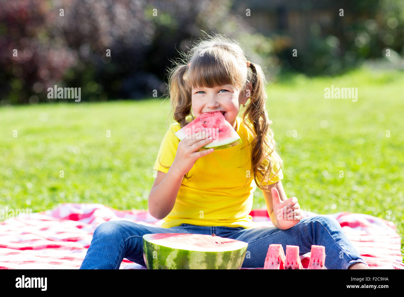 Carino bambina con cocomero sull'erba in estate Foto Stock