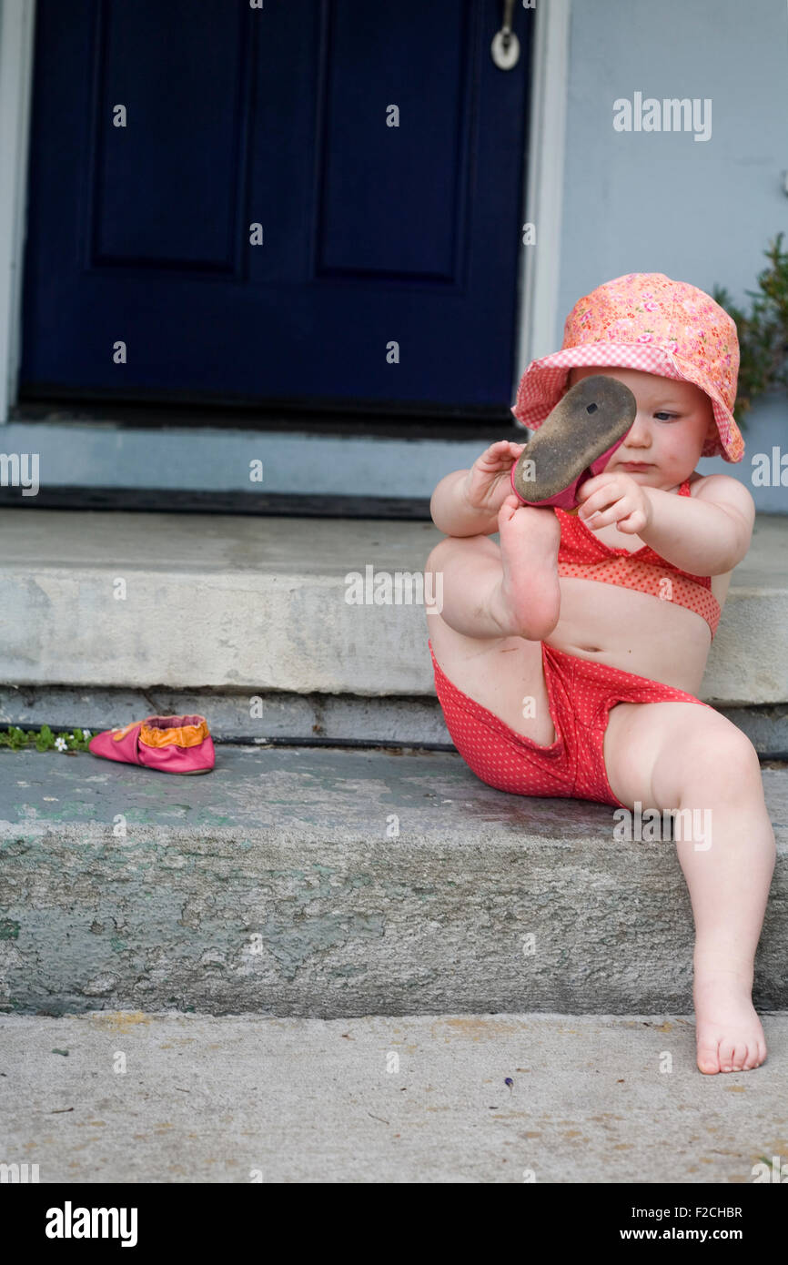 Il toddler girl mette sul pattino esterno sul suo fasi anteriori Foto Stock