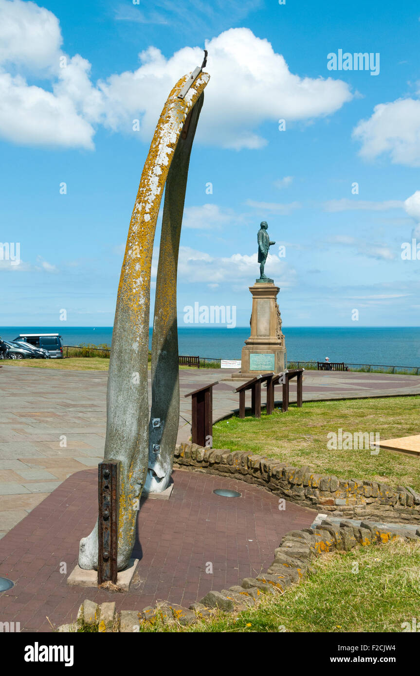 Il whalebone arch sulla West Cliff, Whitby, nello Yorkshire, Inghilterra, Regno Unito. Il Captain Cook statua è dietro. Foto Stock