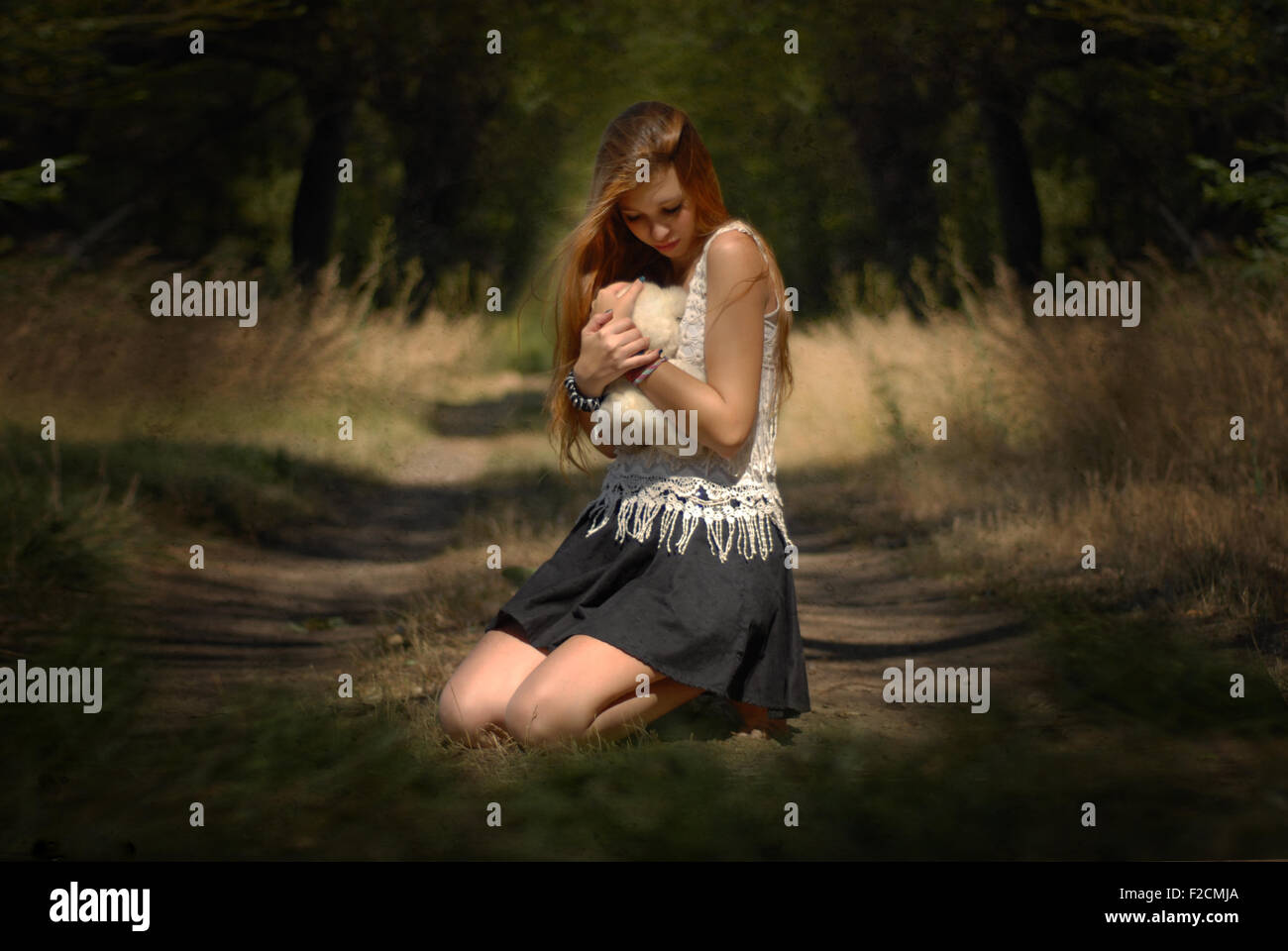 Anima persa e l'innocenza - ragazza abbracciando orsacchiotto nella foresta di piangere ragazza nella foresta con Teddy bear bella luce Foto Stock