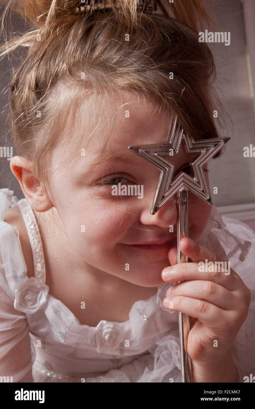 Ritratto di giovane ragazza con a forma di stella wand sorridente e guardando attraverso la bacchetta verso la telecamera Foto Stock