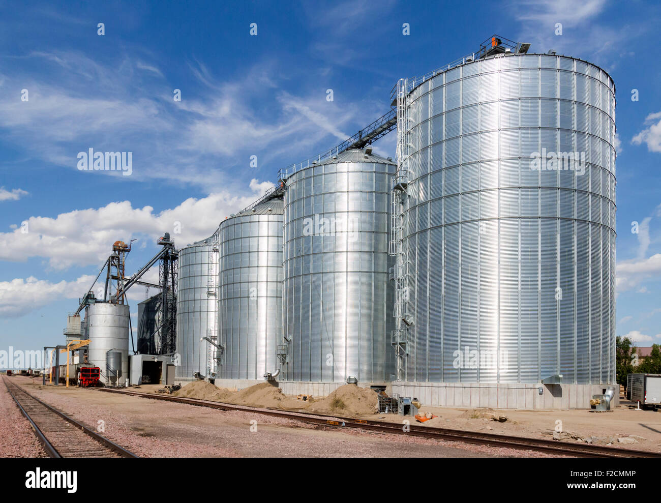 Un treno seduto accanto al metallo di grandi silos per il grano per i prodotti agricoli. Foto Stock