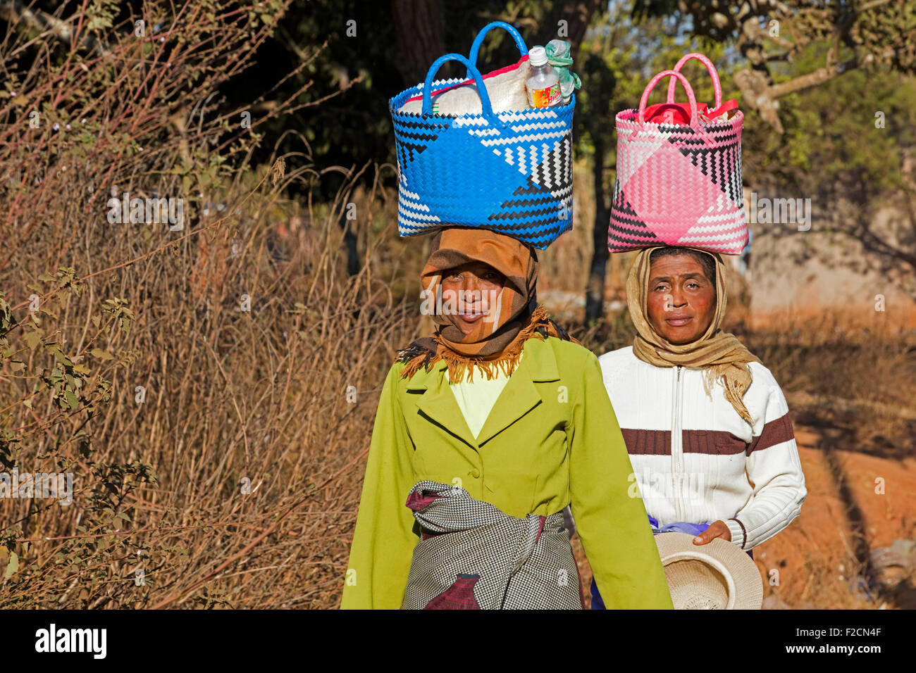 Due donne malgasce con shopping bag sulla loro testa a piedi mercato settimanale Ambalavao, Haute Matsiatra, Madagascar, Africa Foto Stock