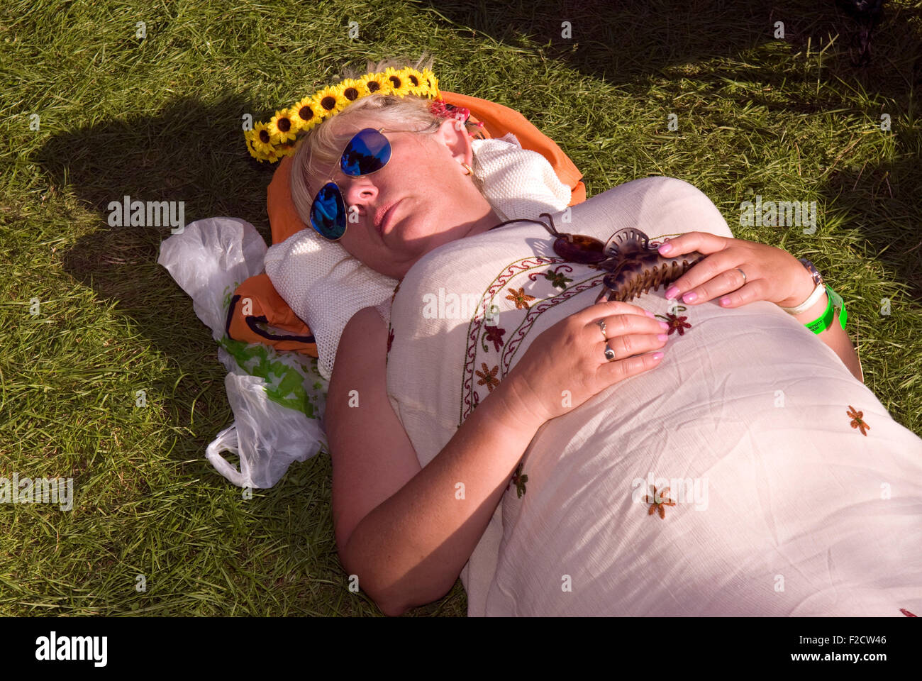 Festival goer prendendo un pisolino all'Weyfest 2015 Festival di musica, la vita rurale centro, Tilford, Farnham, Surrey, Regno Unito. Foto Stock