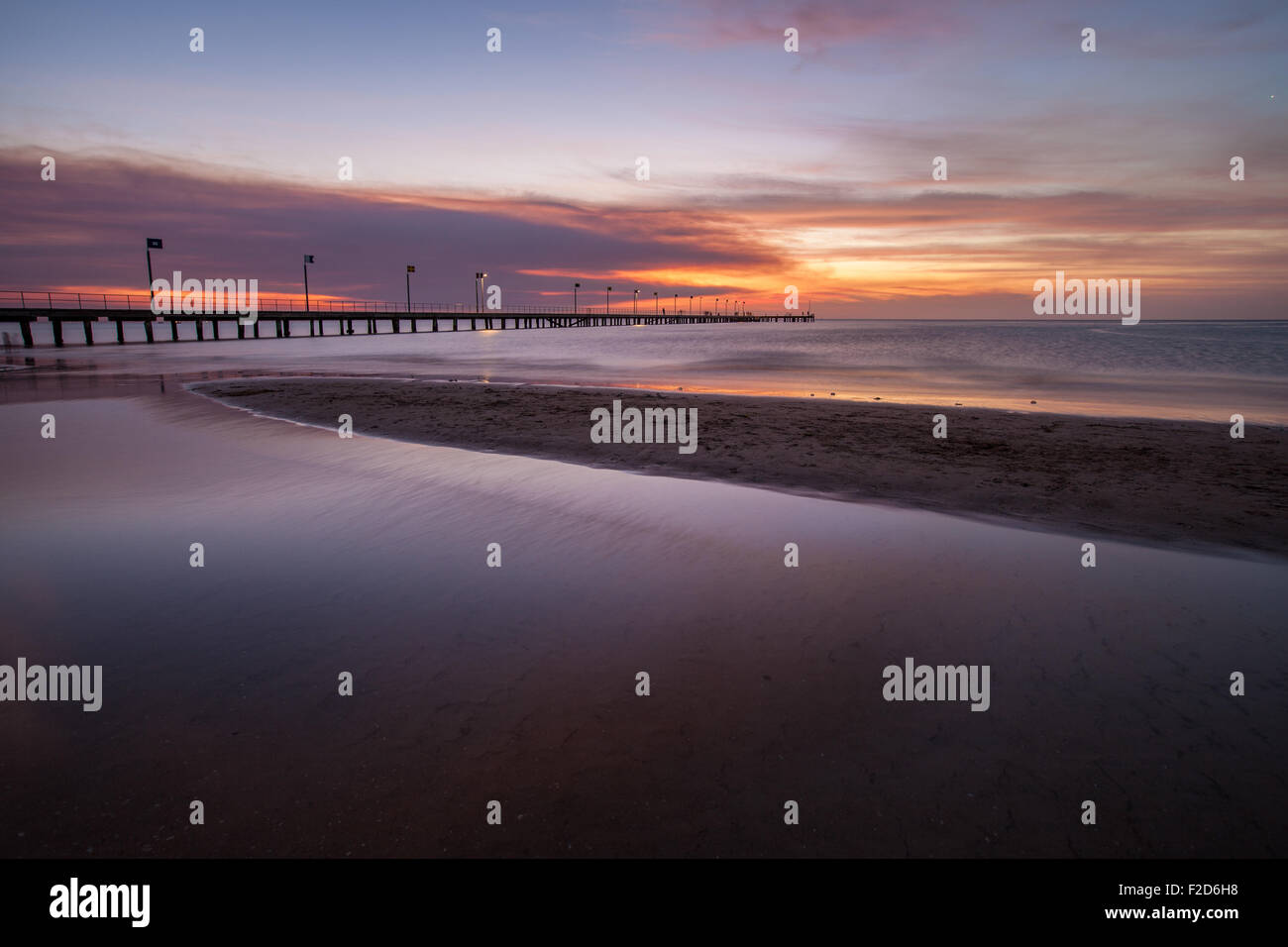 Acqua liscia superficie e pier in arancione tramonto Colori. Foto Stock