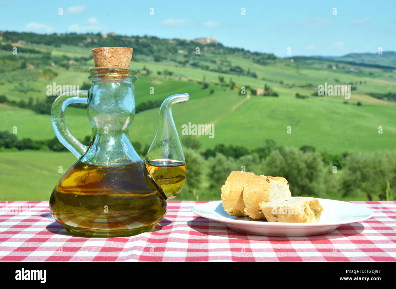 Olio di oliva e il pane sulla tavola contro il paesaggio toscano. Italia Foto Stock