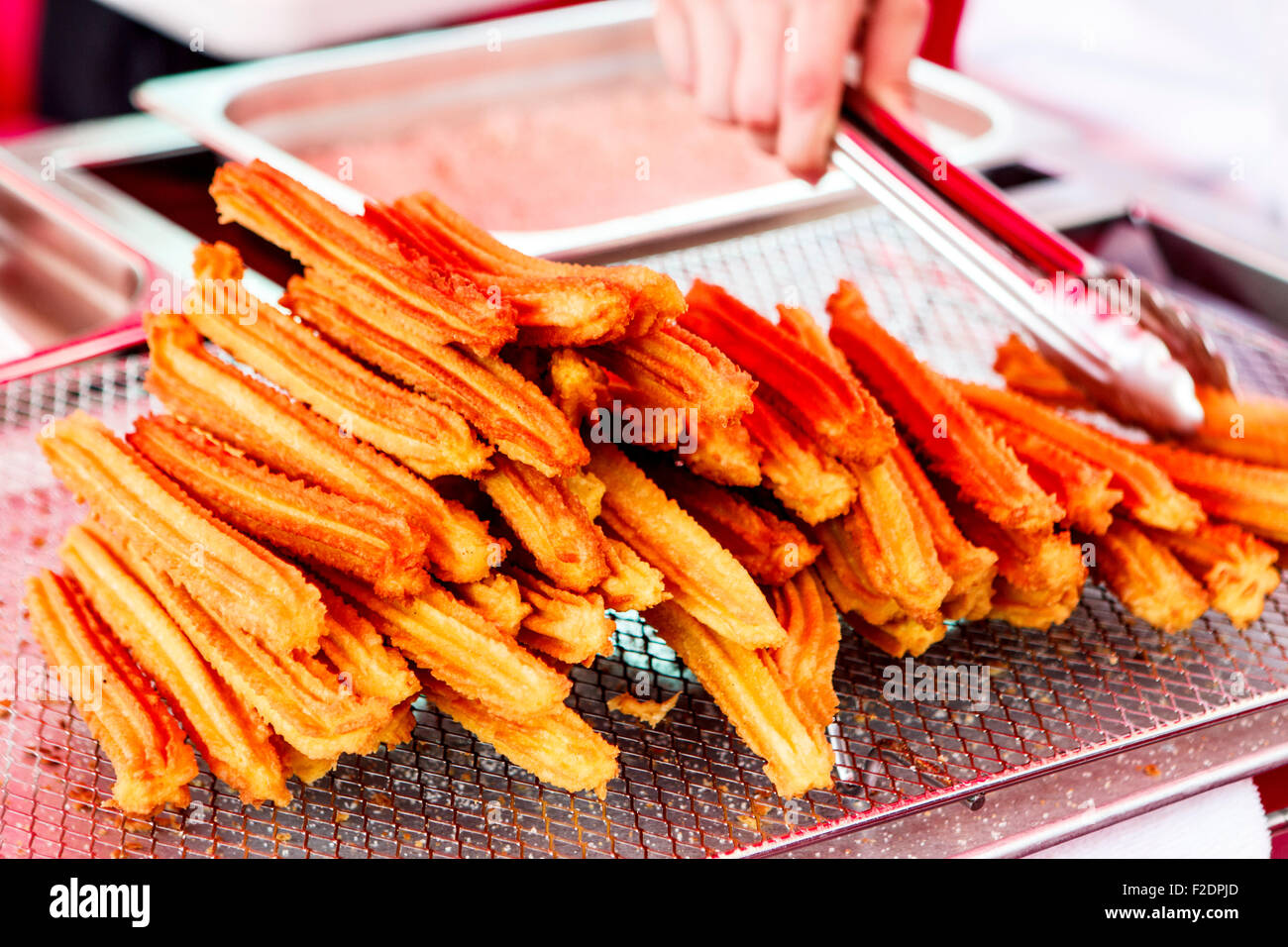 Pila di churros fritti dessert messicano e pinze Foto Stock
